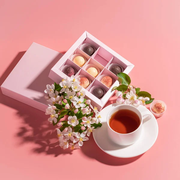 Çeşitli renklerde çikolatalı trüf şekerler. Kutlu çay, pembe arka plan.