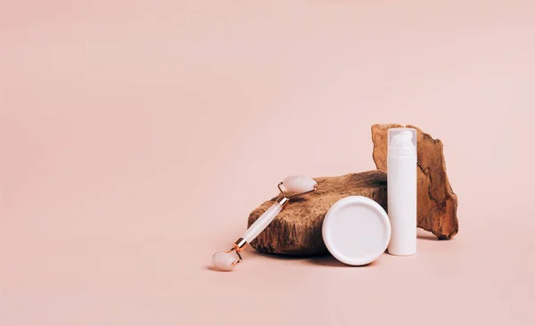 현대의 연단 핑크 배경 위에 안마 구마용 화장품 로울러를 놓는다 — 스톡 사진