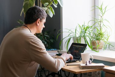 Karantina virüsü sırasında internetten öğrenme konsepti. Genç adam evde dijital dizüstü bilgisayarla çalışıyor.