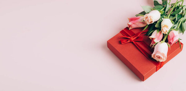 Beautiful fresh roses festive gift box on pastel pink background. Copy space