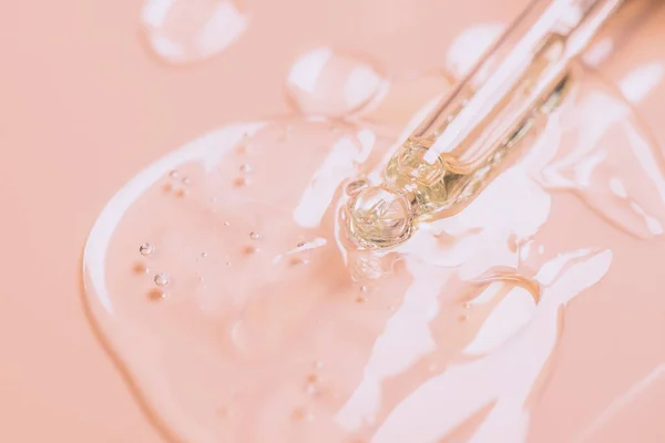 Kozmetik sıvı jel serumu kayganlaştırıcı. Pembe arka plandaki pipetteki hyaluronik asit. Yüz bakımı..