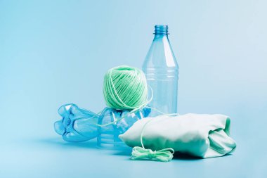 Plastiği geri dönüşüm konsepti. Boş plastik şişe ve geri dönüştürülmüş polyester iplik, sentetik kumaş mavi arkaplan