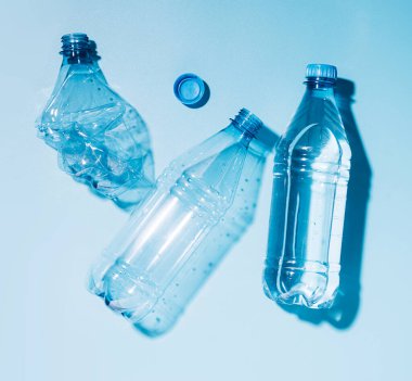 Mavi arka planda su ve boş plastik şişeler kullanılıyor. Geri dönüşümlü plastik. Çevre koruma