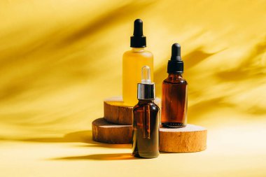 SPA prosedürleri için yüz için kozmetik ürünler. Ahşap podyumlarda gerekli yağ jeli serumu sarı arka planda