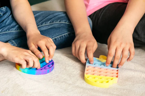 As mãos de crianças jogam o brinquedo brilhante sensorial na moda anti-stress estouram-no. Brinquedo de silicone com bolhas macias aliviar o estresse — Fotografia de Stock