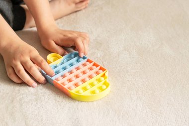 Çocukların elleri, modaya uygun bir anti-stres oyuncağı oynar. Çocuk yumuşak baloncuklu silikon bir oyuncakla oynuyor.