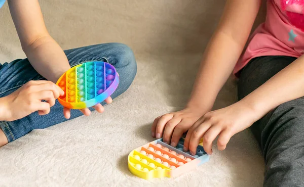 As mãos de crianças jogam o brinquedo brilhante sensorial na moda anti-stress estouram-no. Brinquedo de silicone com bolhas macias aliviar o estresse — Fotografia de Stock