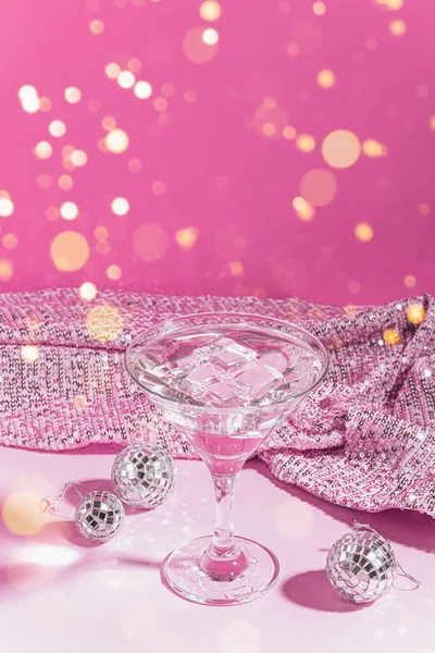 Martini koktajl różowy uroczyste tło z błyszczącymi kulkami disco. Klasyczny napój alkoholowy z lodem w eleganckiej szklance na świętowanie. — Zdjęcie stockowe
