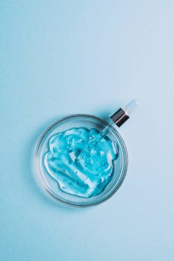 Kozmetik Sıvı Jel Serumu Kayganlaştırıcı Hyaluronik asit Cam labaratuvar kabarcıkları mavi arka plan