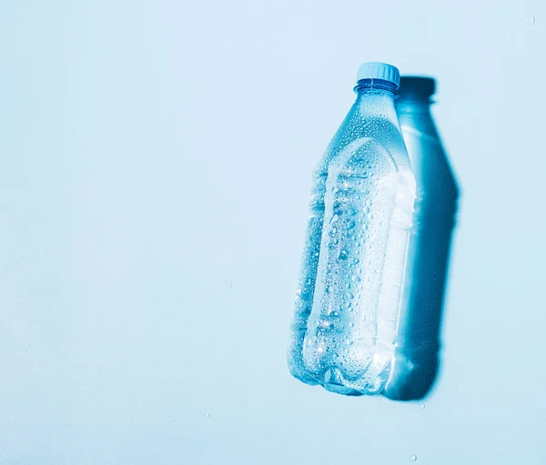 Pure drinking mineral water in a transparent plastic bottle on a blue background.