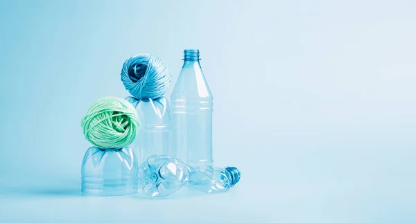 Plastic recycling and reuse concept. Empty plastic bottle and polyester fiber synthetic thread on a blue background.