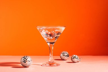 Zarif bir bardak disko topunun içinde, parlak pembe arka planda buzlu martini. Moda, parlak, doğrudan ışık. 