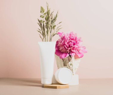 Çeşitli kavanoz ve tüplerdeki kozmetik ürünler soyut modern arka plan. Doğal malzemelerden podyum taze çiçekler