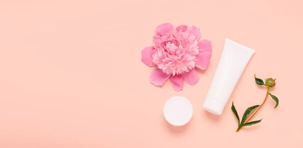 Productos cosméticos crema gel champú bálsamo en varias botellas sobre un fondo rosa con flores frescas peonías — Foto de Stock