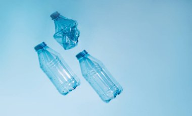 Mavi arka planda buruşmuş plastik şişeler kullanılmış. Geri dönüşümlü plastik. Kirlilik, çevre koruma.