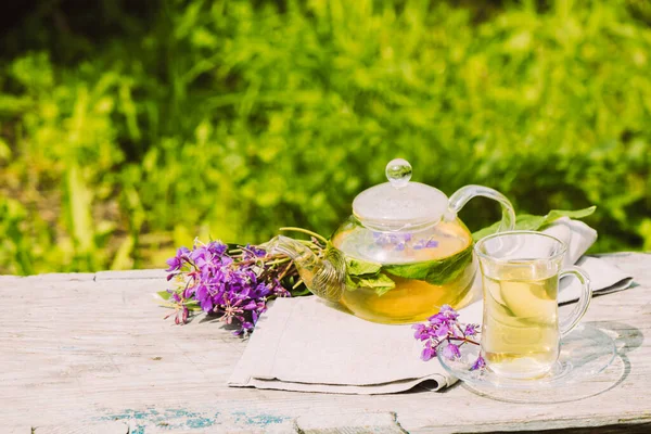 Taze limonlu çay, yaz bitkileri cam bardakta yonca yaprakları ve ahşap kırsal arka planda çaydanlık. — Stok fotoğraf