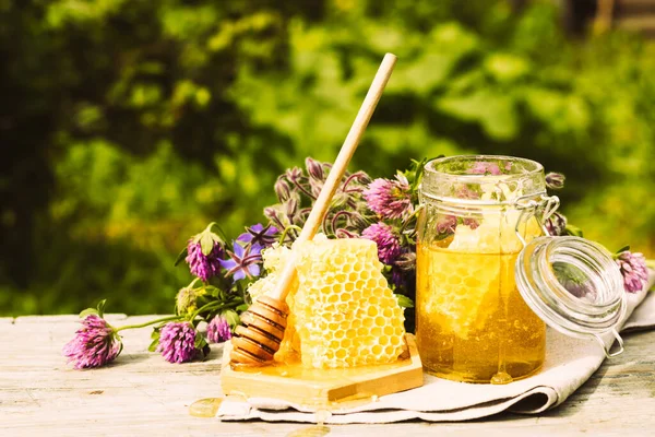 Miele fresco in un barattolo di vetro su uno sfondo rurale estivo. Dolce dessert floreale profumato al miele, vista frontale — Foto Stock