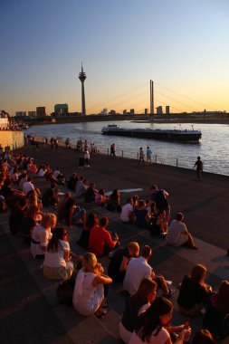 Birçok insan Duesseldorf 'taki Rheintreppe' de gün batımının tadını çıkarıyor. Muhteşem Rhein Nehri manzarası harika.
