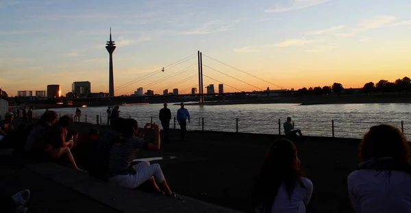 许多人在杜塞尔多夫的莱茵特鲁佩欣赏日落 欣赏雄伟壮丽的莱茵河美景 — 图库照片