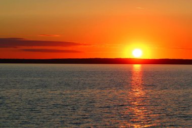 Güneş, büyük bir gölün sonunda dağların ardında kaybolur.