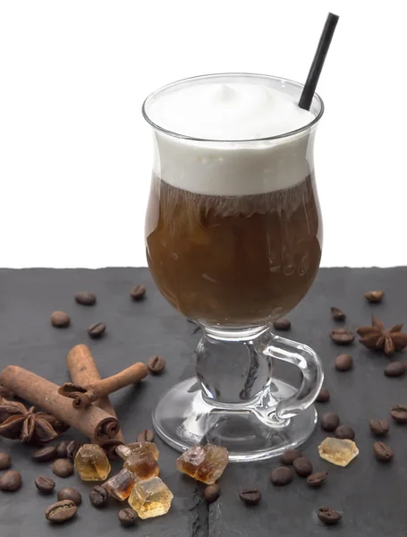 Bebida caliente en vaso con espuma de leche café con leche, capuchino, moccachino con tubo, en la mesa negra. Cerca de los palitos de canela, anís y azúcar de caramelo — Foto de Stock