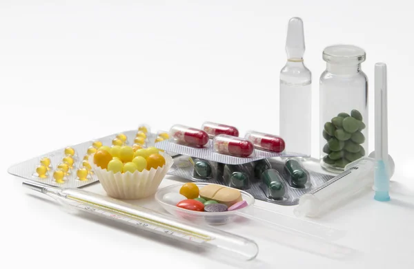 Spuit, thermometer, tabletten en capsules in blaren geïsoleerd — Stockfoto