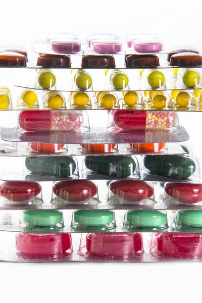 Comprimidos coloridos, cápsulas e vitaminas em blisters no fundo branco — Fotografia de Stock