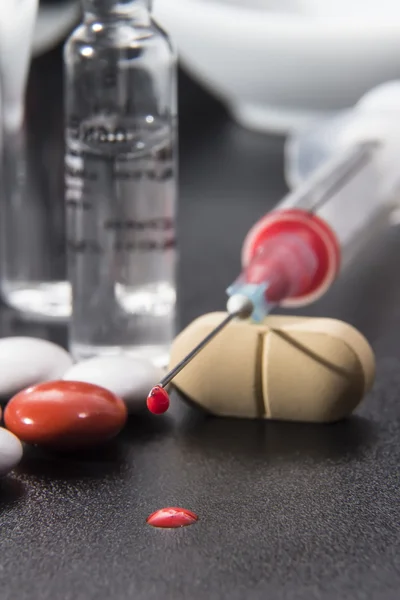 Spuit met medicatie, capsules en tabletten op een zwarte achtergrond — Stockfoto