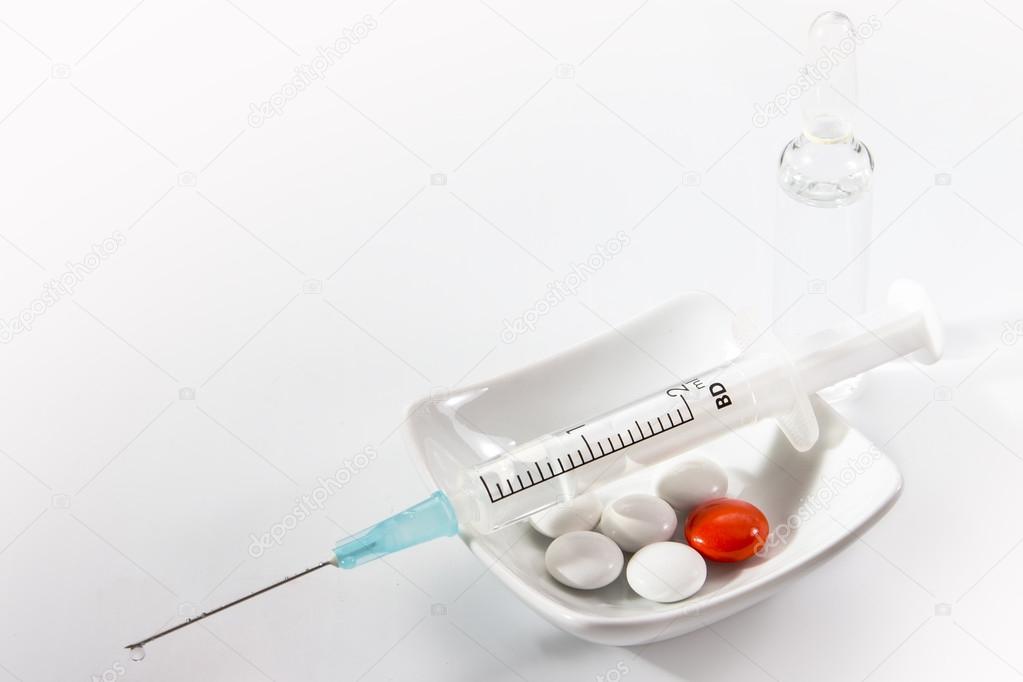 syringe with medication, capsules and tablets on white background