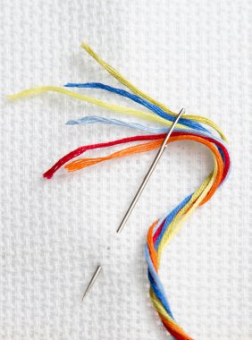 white canvas for embroidery and needle with colored thread embroidery floss, passion and work