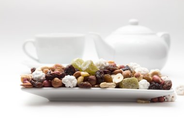 mixture of nuts and dried fruits are on the plate, background of the coffee maker, cups white closeup
