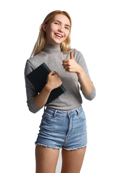 Onunla birlikte genç öğrenci el başparmak-up jest, veren gülümseyen ve kameraya bakıyor kitap