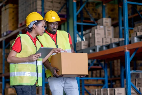 Afrika kökenli Amerikalı bir depo çalışanı ya da fabrika işçisi iş yerinde tutulan ürün kutusu hakkında konuşuyor. Çalışan personelin iyi yönetimi kavramı.