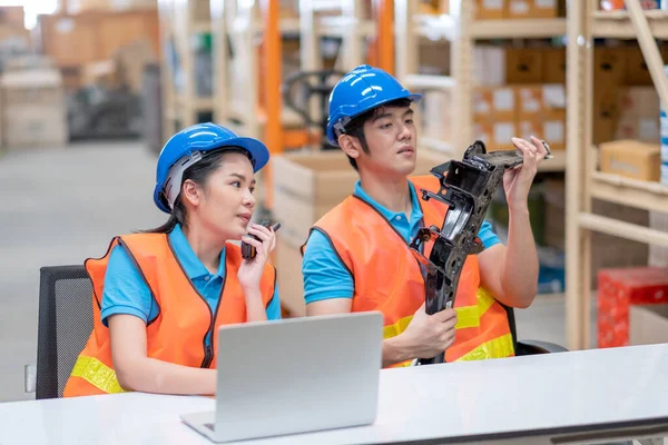 Warehouse man and woman or factory workers sit on chairs and discuss together about stock of automotive parts in workplace area. Concept of good management and happiness in industrial business.