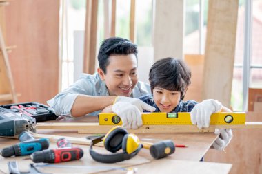 Asyalı bir baba oğluna evlerindeki marangozluk seviyesini ölçmek ve ayarlamak için kullanmayı öğretir. Hobi ile iyi ilişki kavramı ya da mutlu aile aktiviteleri.