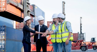 Bir grup kargo konteynırı işçisi ya da fabrika işçisi ve mühendis iş yerinde el koordinasyonu gösteriyor. İyi takım çalışması kavramı endüstriyel sektörün en başarılı çalışması.