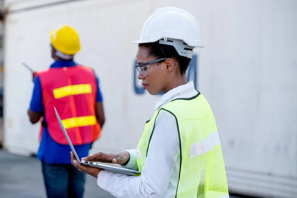 American African technician worker woman touch and look to laptop while her co-worker use walkie-talkie to communicate other. Concept of good system and manager support for better industrial business.