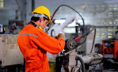 Fabrika işçisinin arkası, çalışma alanındaki robot makinenin tamir ve onarım için alet kullanır. Sanayi ve teknoloji destek sistemi, çalışan kavramının çalışmasına yardımcı olur.