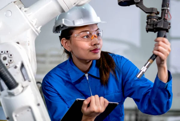 Close up factory worker woman maintenance and check part of robotic machine in workplace area. Industrial and technology support system help in working of employee concept.