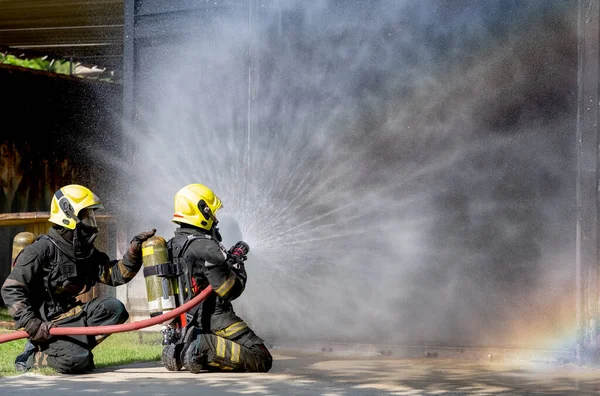 Dos Bomberos Sientan Suelo Pulverizan Agua Con Forma Cortina Reflejo —  Fotos de Stock