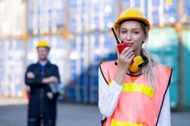 Kargo konteyneri kadın işçisi ya da ustabaşı ekibiyle ve diğer teknisyenlerle konuşmak için telsiz kullanıyor..