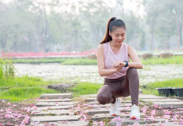 Azjatka Odzieżą Sportową Joggingu Siedzi Patrzy Zegarek Podczas Ćwiczeń Ogrodzie — Zdjęcie stockowe