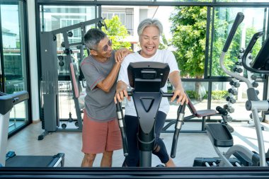 Spor salonunda spor yaparken yaşlı bir bayanın yanında durup ona sarıl. Gülümseyerek mutlu görünüyorlar..