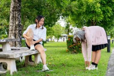 Asyalı son sınıf öğrencisi kadın oturur ve arkadaşına arka bahçeyi gün ışığında germesi için rehberlik eder..
