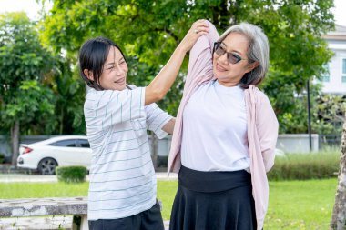 Asyalı son sınıf öğrencisi, arkadaşının kollarını ve omuzlarını gün ışığıyla esnetmesine yardım ediyor..