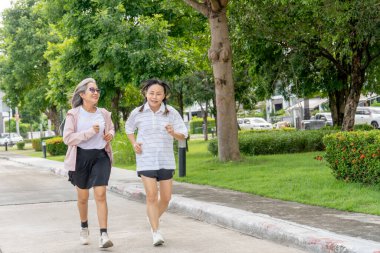 İki Asya 'lı son sınıf öğrencisi gün ışığında bahçede koşu yapıyor..