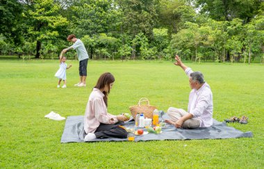 Büyükbaba, gün ışığında babasıyla birlikte parktan zevk alan küçük kızla el sallamak için elini kaldırdı.