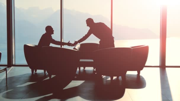 Silhouetten van twee zakenlieden handshaking en praten — Stockvideo