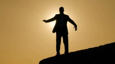 Gün batımında eller yükselterek adam silüeti