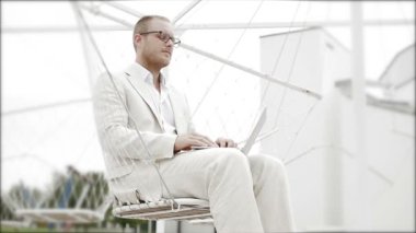 Salıncakta oturan dizüstü bilgisayarda çalışan adam